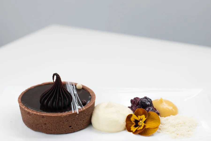 Chocolate Tart (NF) Berry compote – White balsamic crisps – Stone fruit coulis Chocolate Tart (NF) Berry compote – White balsamic crisps – Stone fruit coulis