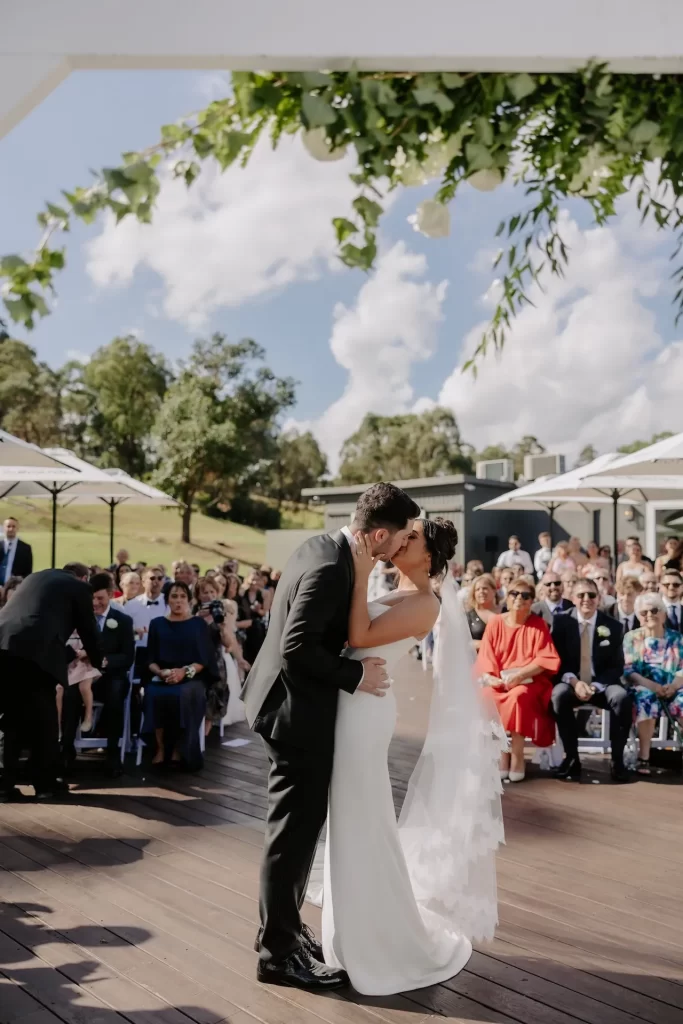 Bride and groom kissing after outdoor wedding ceremony
