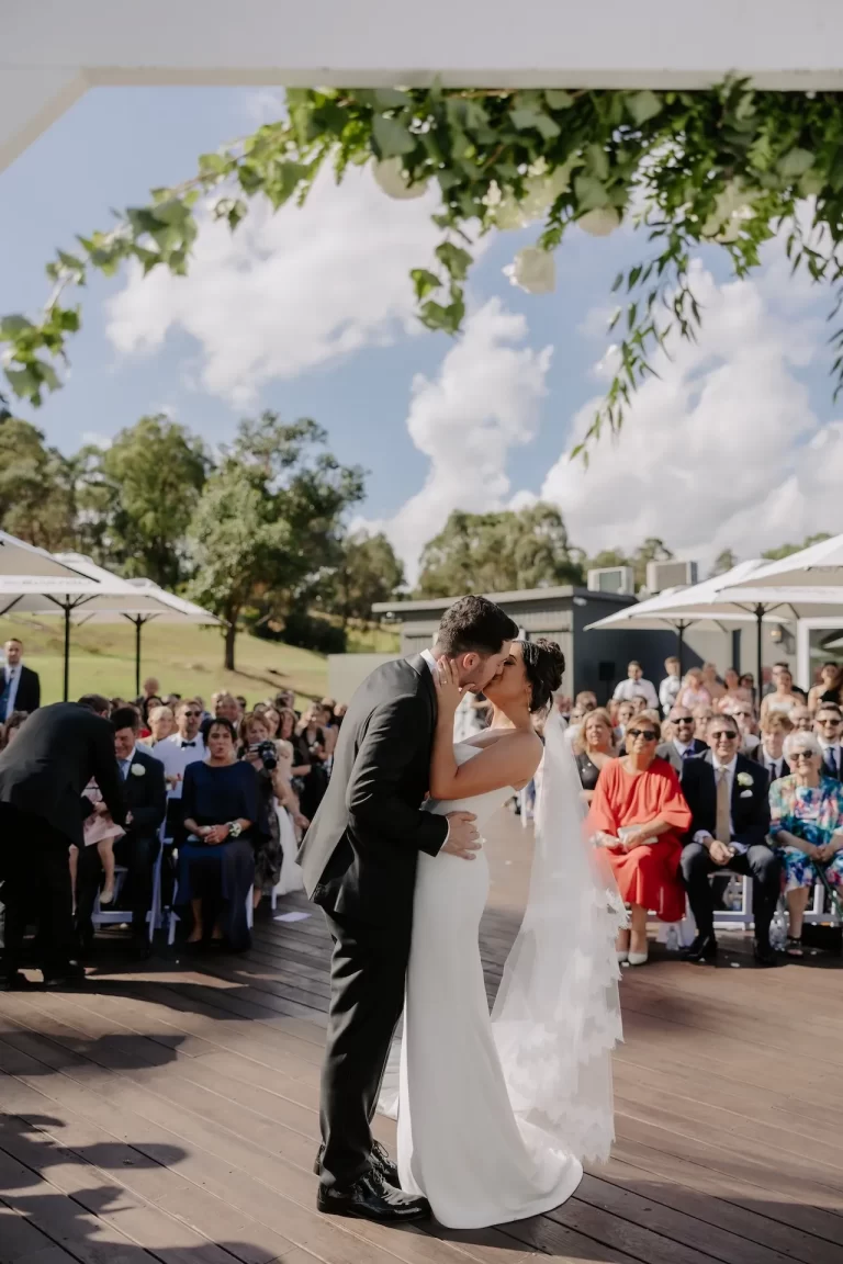 Bride and groom kissing after outdoor wedding ceremony